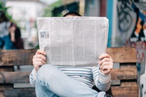 Man sitting on bench with newspaper in front of face for PR Strategies for small businesses